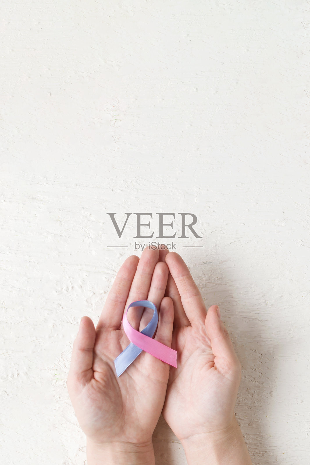 世界甲状腺日。世界癌症日。妇女的手握甲状腺癌意识缎带青色粉红蓝色白色背景。甲状腺的问题。多囊病。照片摄影图片