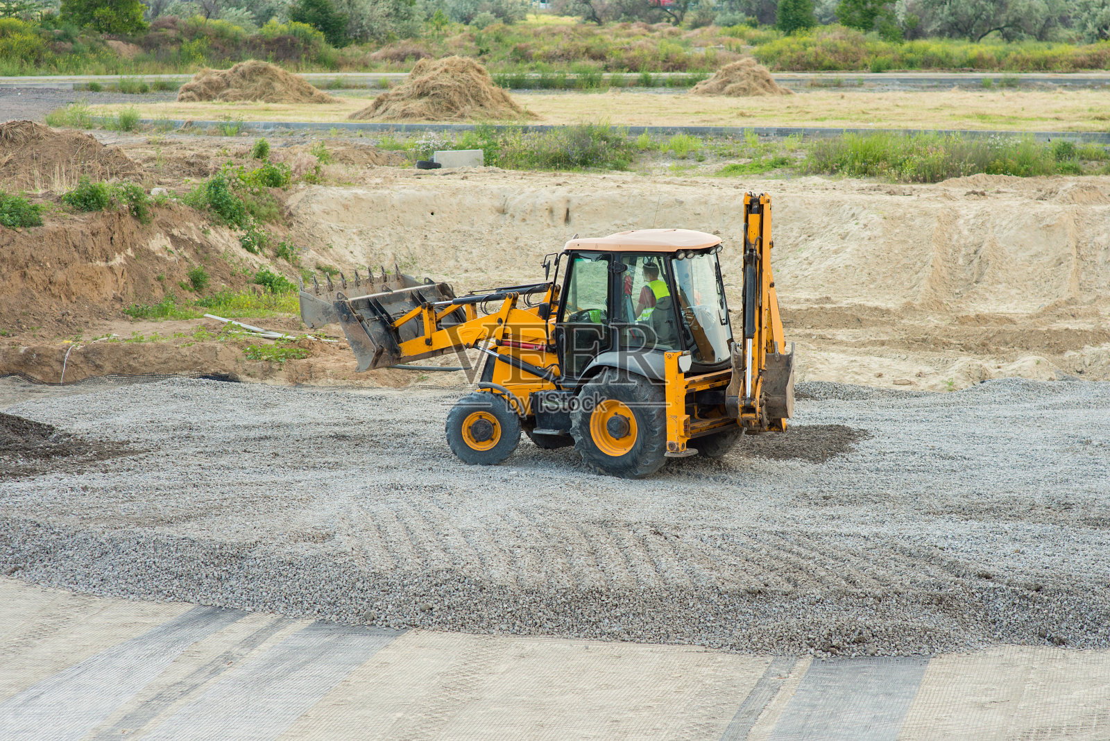 黄色挖土机在建筑工地上铲平碎石照片摄影图片