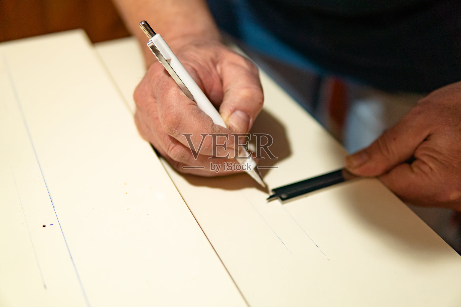 近距离观察,人类的双手用尺子测量并在一块木板(胶合板)上做记号,为自己的家做家具。在家DIY项目。照片摄影图片