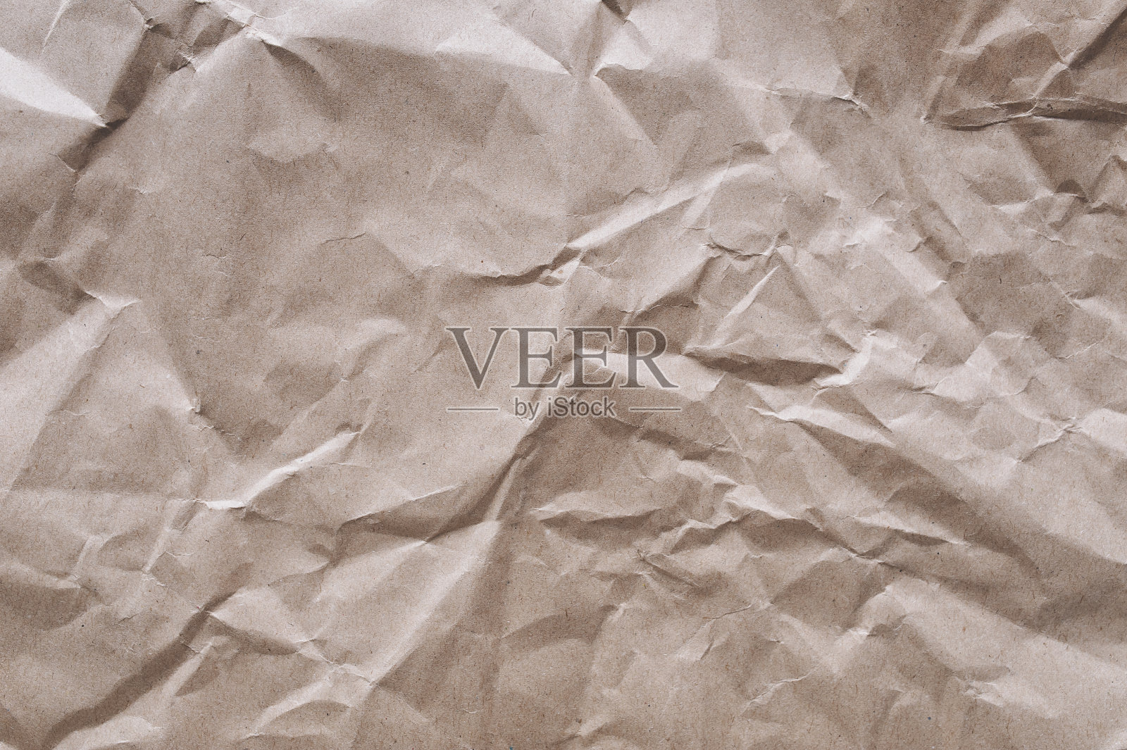 背景来自旧的皱巴巴的浅棕色包装纸。由可回收材料制成的纸板的质地。照片摄影图片