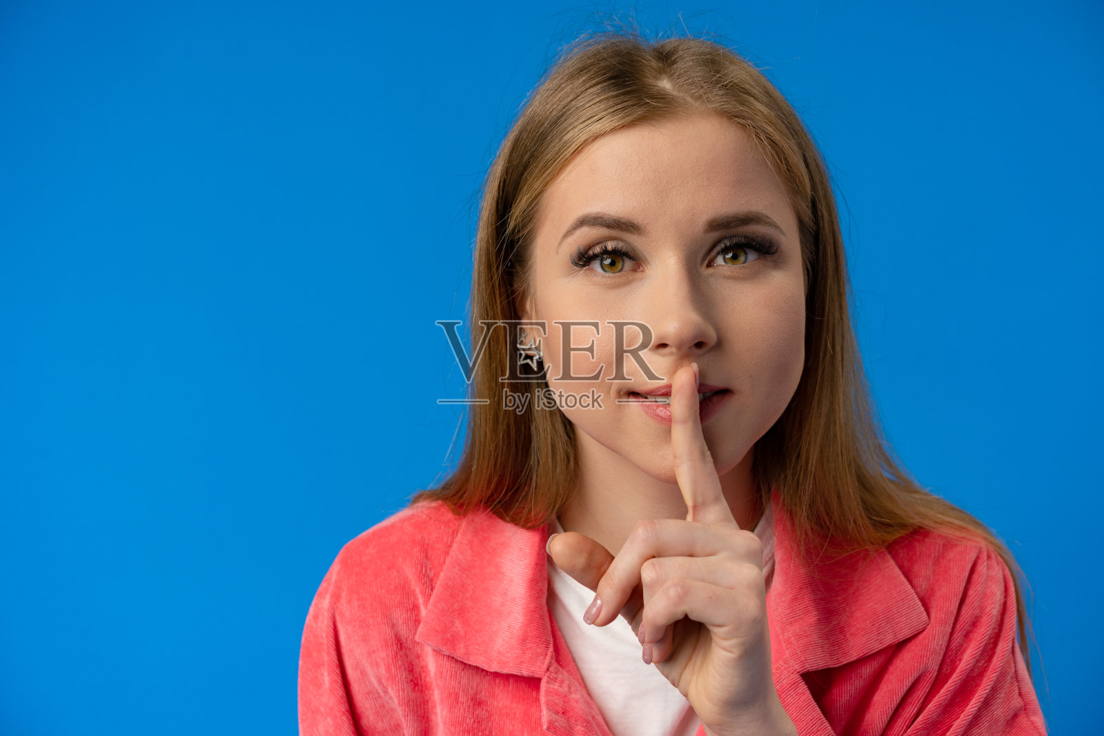 年轻漂亮的女人在蓝色的背景下展示沉默的手势照片摄影图片