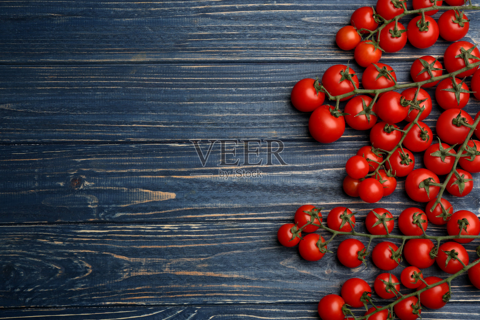 新鲜成熟的樱桃番茄放在蓝色的木桌上,平放。空间的文本照片摄影图片