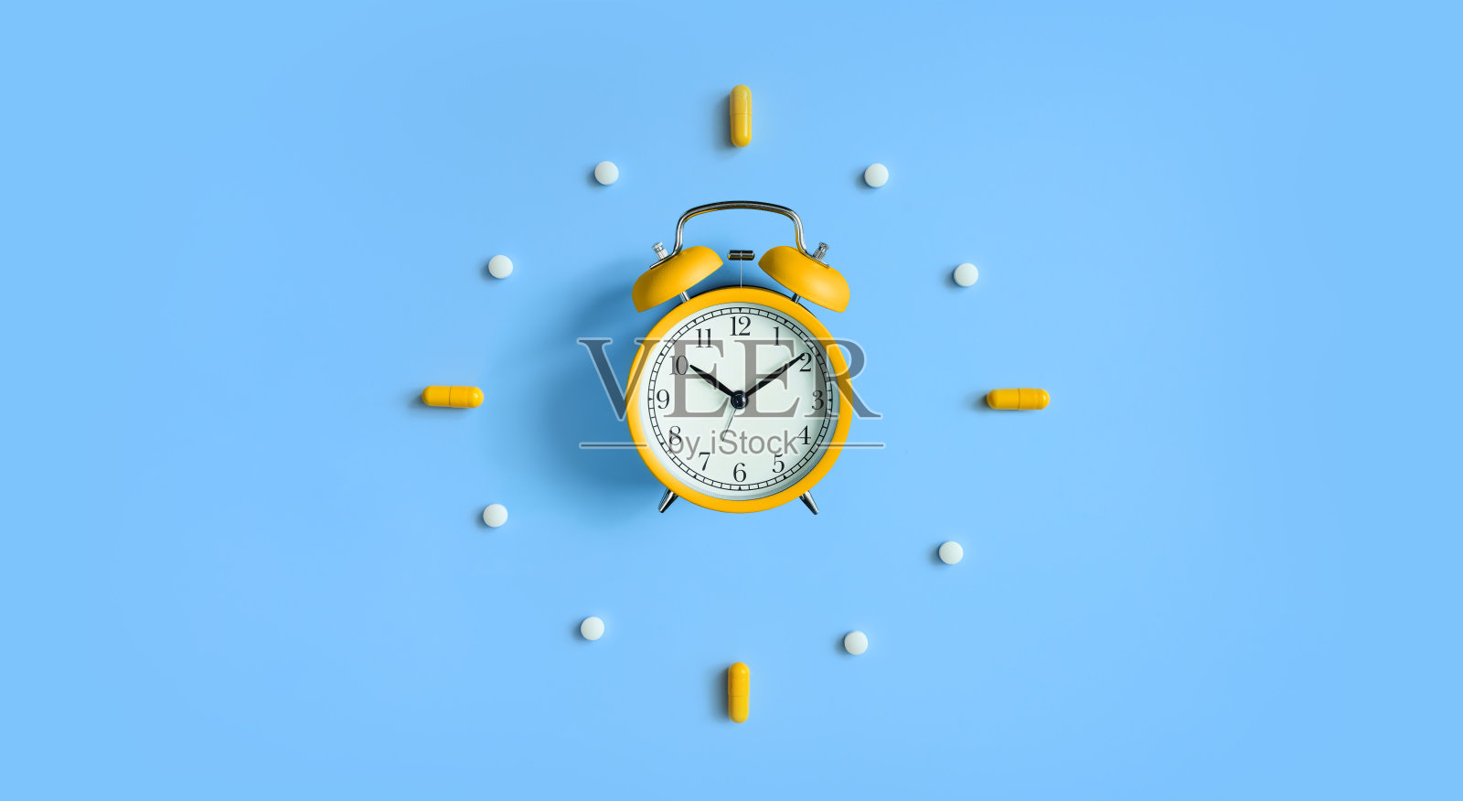闹钟与药丸,蓝色背景的医疗胶囊照片摄影图片