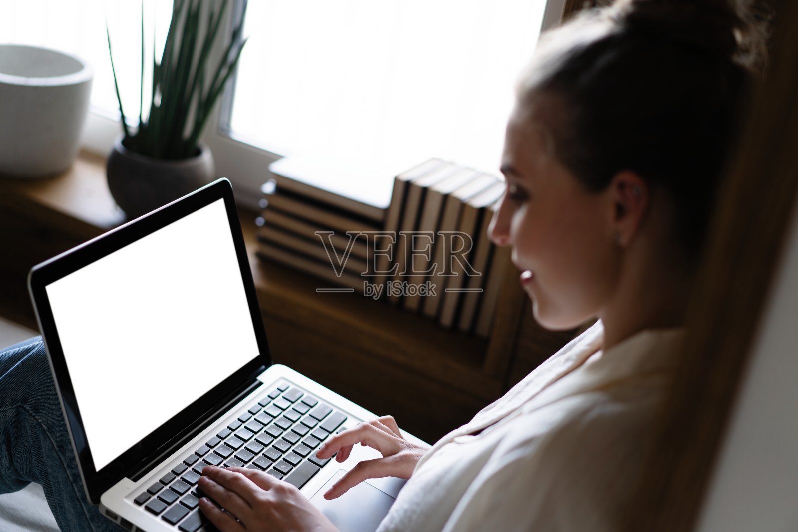 一个女人使用和打字在笔记本电脑键盘与空白的白色桌面屏幕的模型图像。照片摄影图片