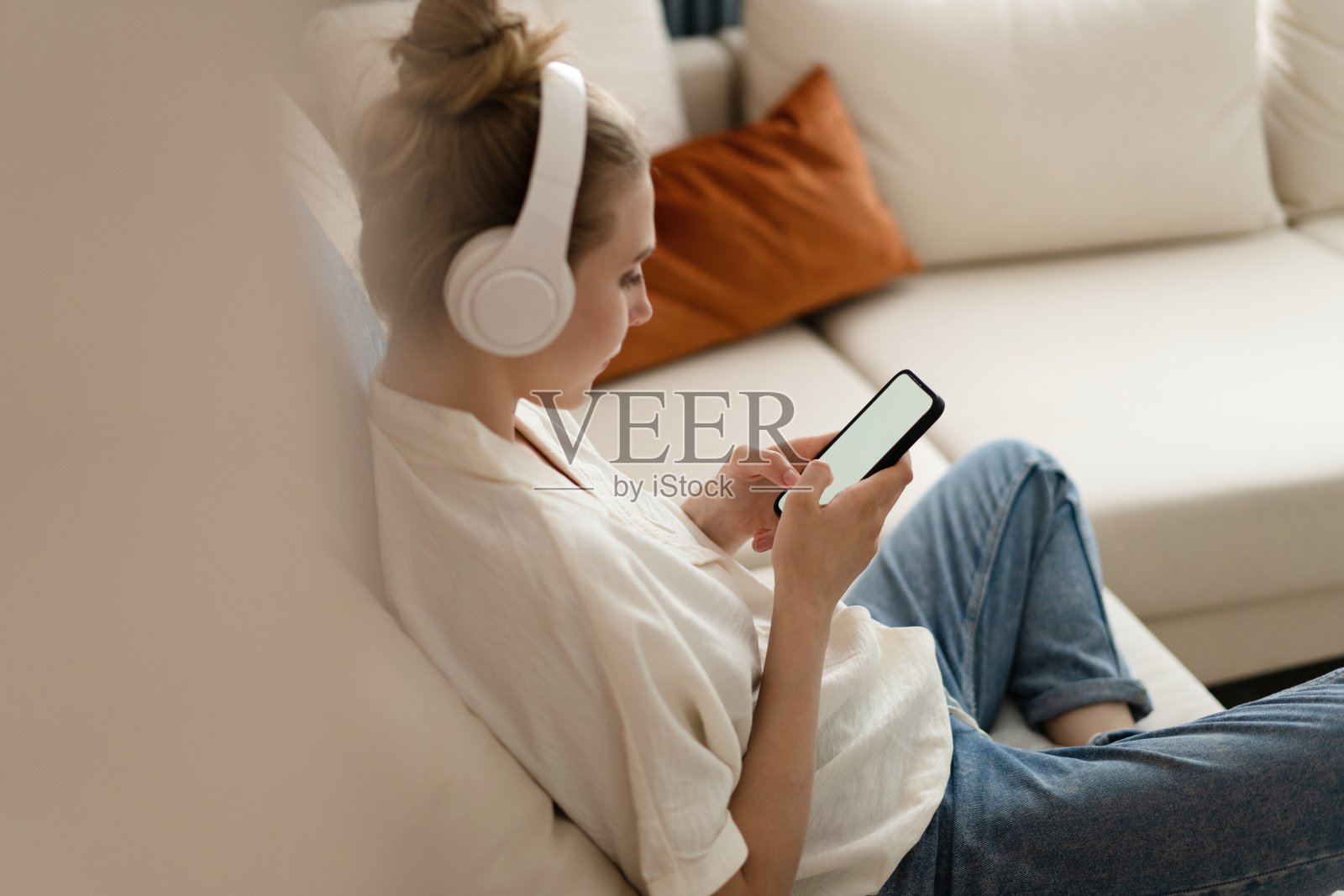 一名年轻女子拿着智能手机触摸手指,在家里用空白屏幕展示社交媒体应用程序广告照片摄影图片