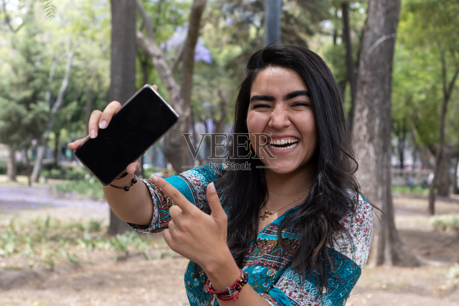 一个女人在公园里用手机照片摄影图片