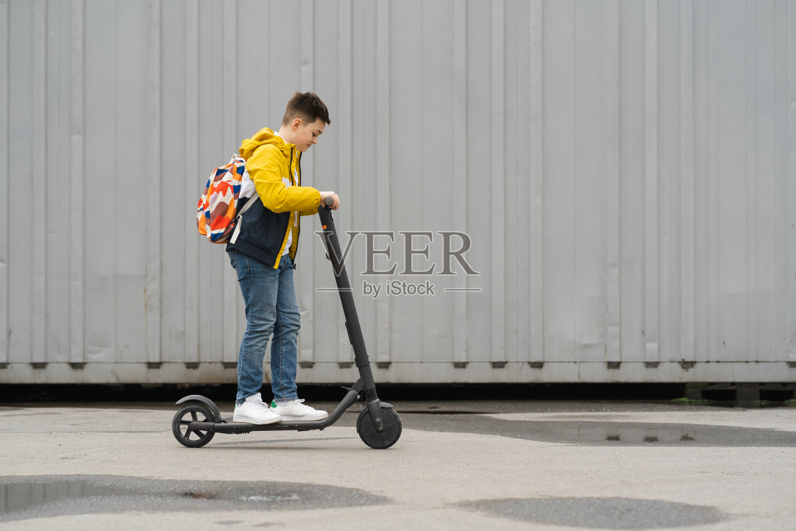 一个背包少年骑着电动滑板车照片摄影图片