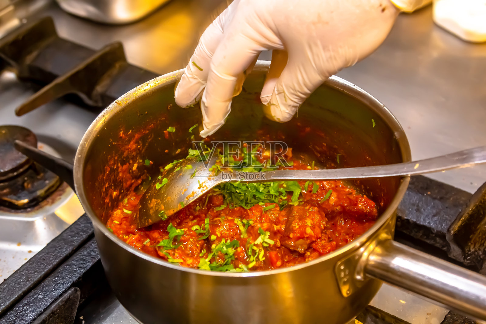 厨师准备了一锅炖肉和又红又热的番茄酱照片摄影图片