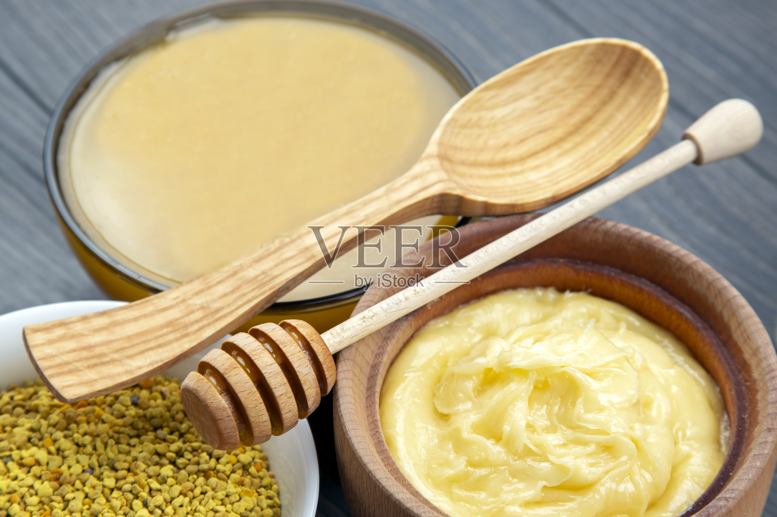 不同品种的新鲜花蜜,花粉和蜂巢与勺子木制背景。有机维生素保健食品照片摄影图片