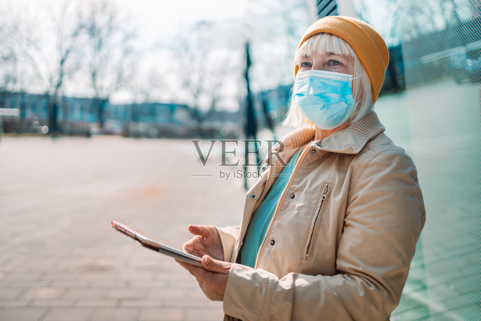 图为,50多岁的中年妇女在户外办公大楼附近使用平板电脑照片摄影图片