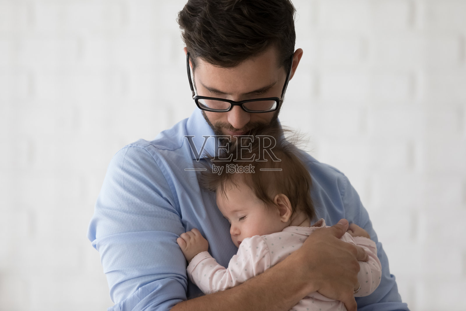 年轻安详的爸爸戴着眼镜抱着困倦的女儿照片摄影图片