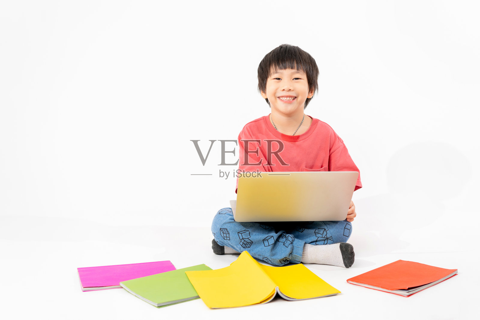 快乐亚洲男孩的肖像在地板上与笔记本电脑和书籍隔离在白色背景,教育和学习与技术概念照片摄影图片