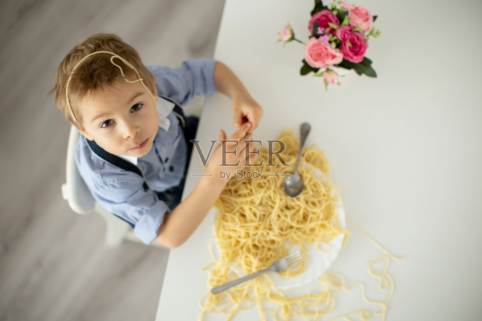 可爱的学前班孩子,金发男孩,在家吃意大利面,把家里弄得一团糟照片摄影图片