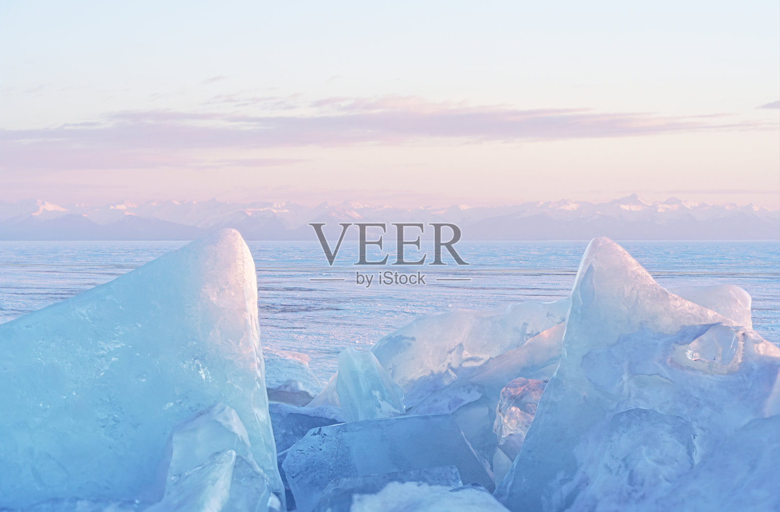 冬天的景观,冰丘在阳光下闪闪发光,西伯利亚的贝加尔湖山脉在日落。照片摄影图片