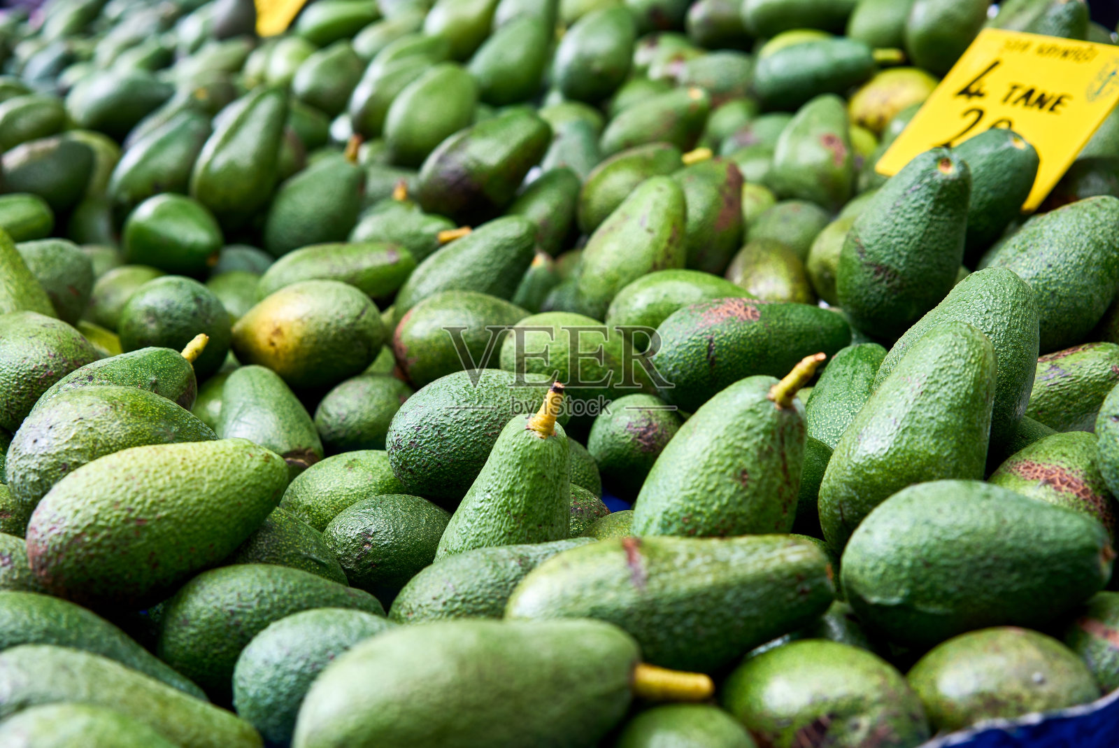 超市的货架上堆放着许多鲜亮美味的绿色鳄梨。照片摄影图片