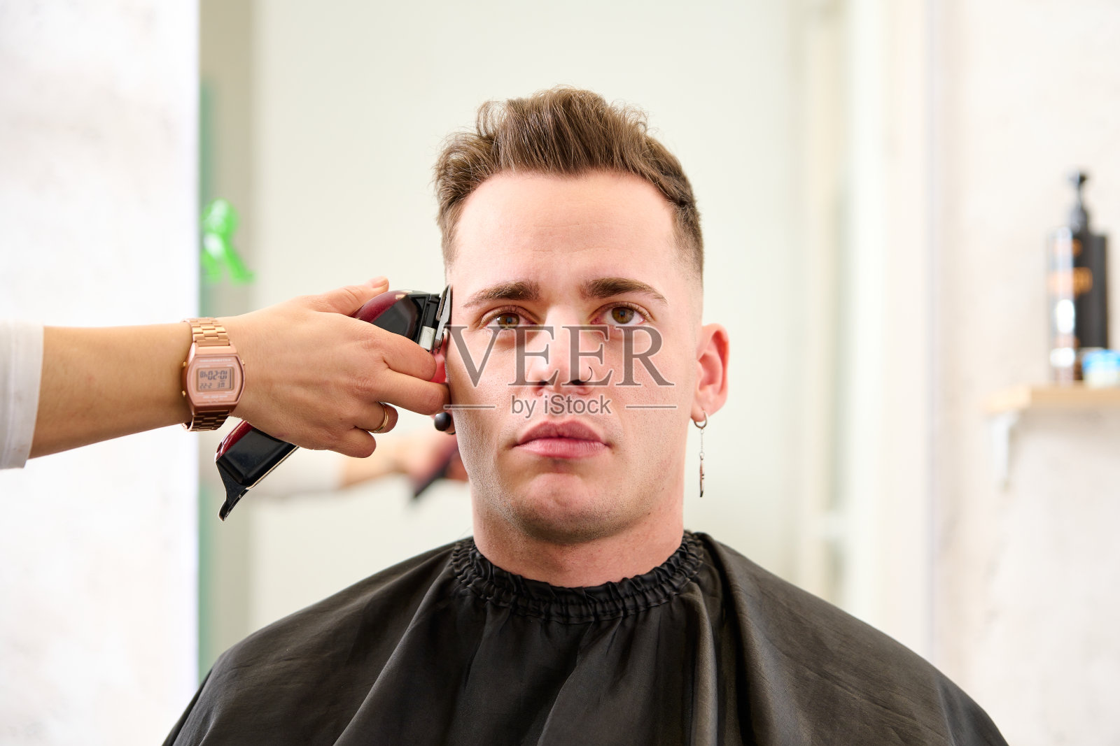 一个男人坐在理发店里,理发师正在用电剪给他理发照片摄影图片