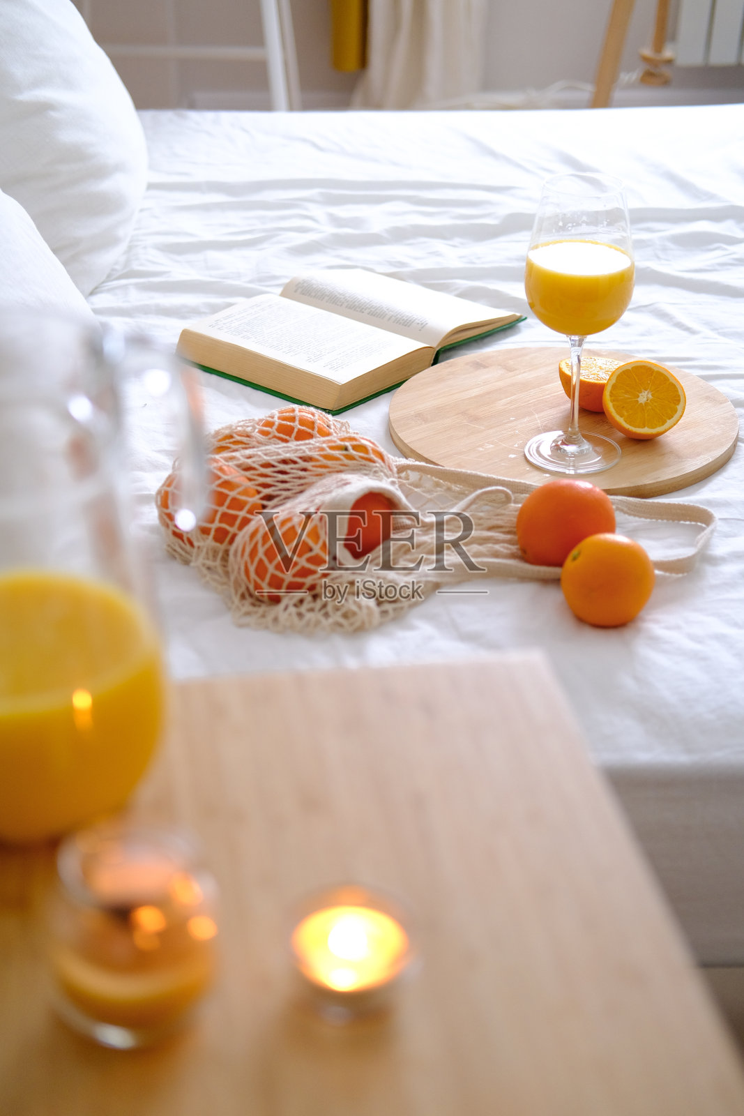 白色的床上放着橙子和橙汁照片摄影图片