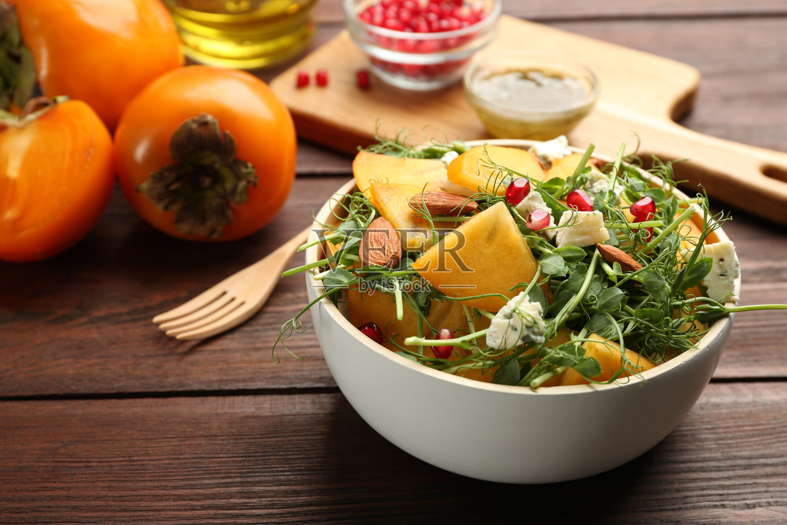 美味的柿子沙拉,石榴和蓝纹奶酪放在木桌上照片摄影图片