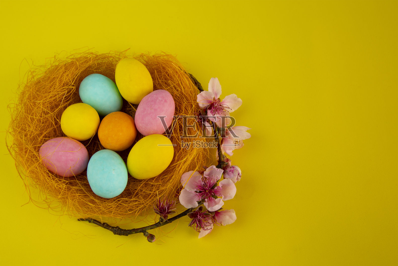 复活节快乐!复活节卡片,黄色的背景上有一窝彩色的蛋,上面装饰着花朵照片摄影图片