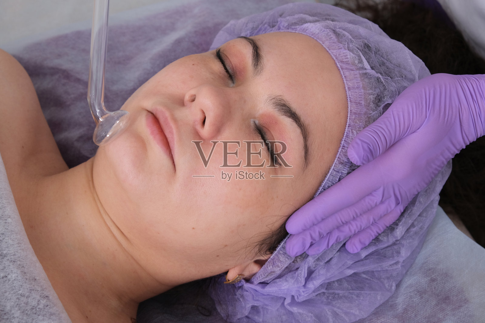 美容师在美容院为客户做脱皮手术。侧视图。专业护肤理念。照片摄影图片