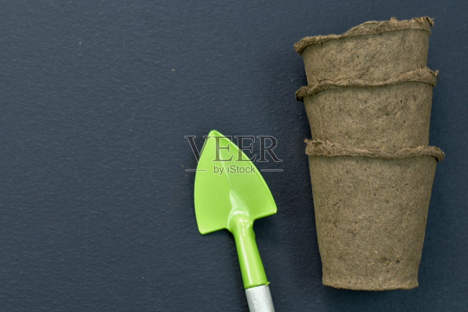 泥炭锅与一个小的花园工具在黑色的背景上。特写镜头。俯视图照片摄影图片