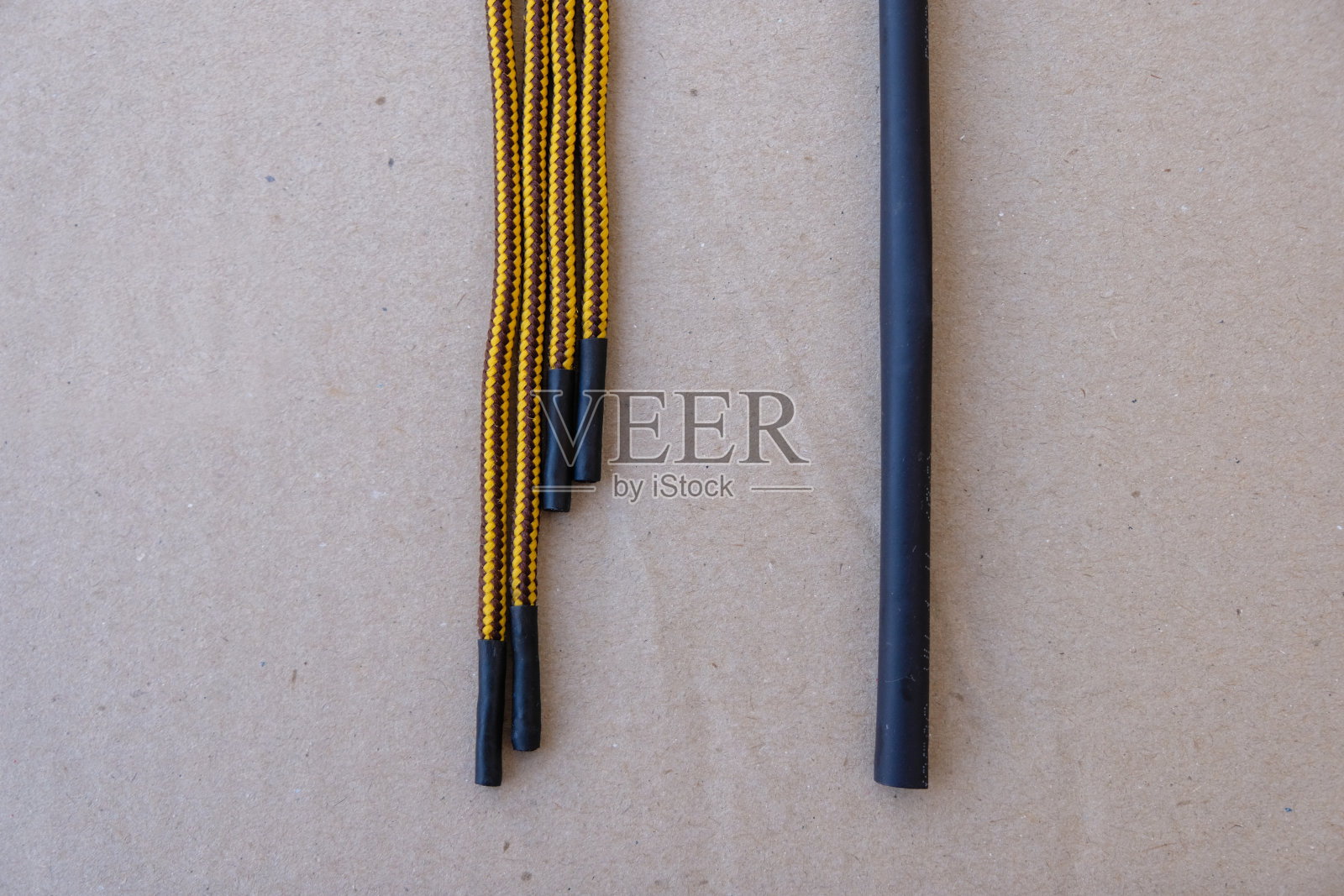 热缩套管和黄色鞋带在灰色的纸上。修补家里破旧的鞋带。照片摄影图片