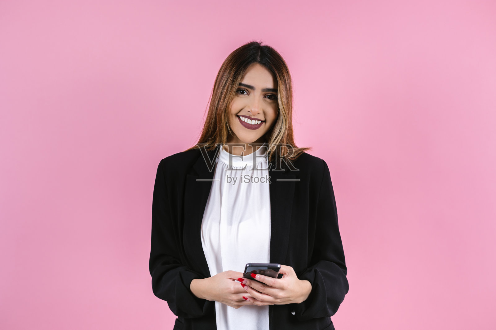 在墨西哥拉丁美洲,一名年轻的西班牙裔女商人在粉红色背景下对着镜头微笑照片摄影图片