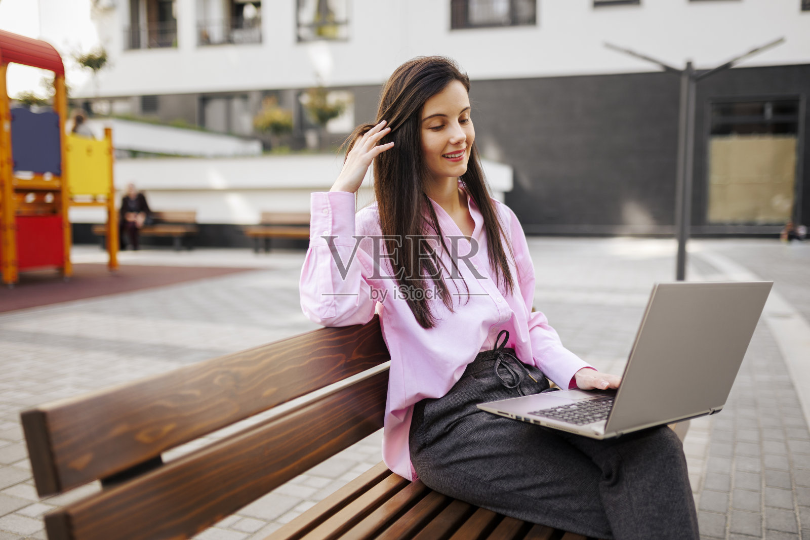 女商人坐在公园的长椅上用笔记本电脑工作照片摄影图片