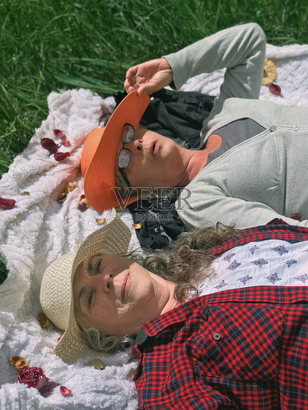 戴着草帽的姐姐们,在草地上嬉笑玩耍。照片摄影图片