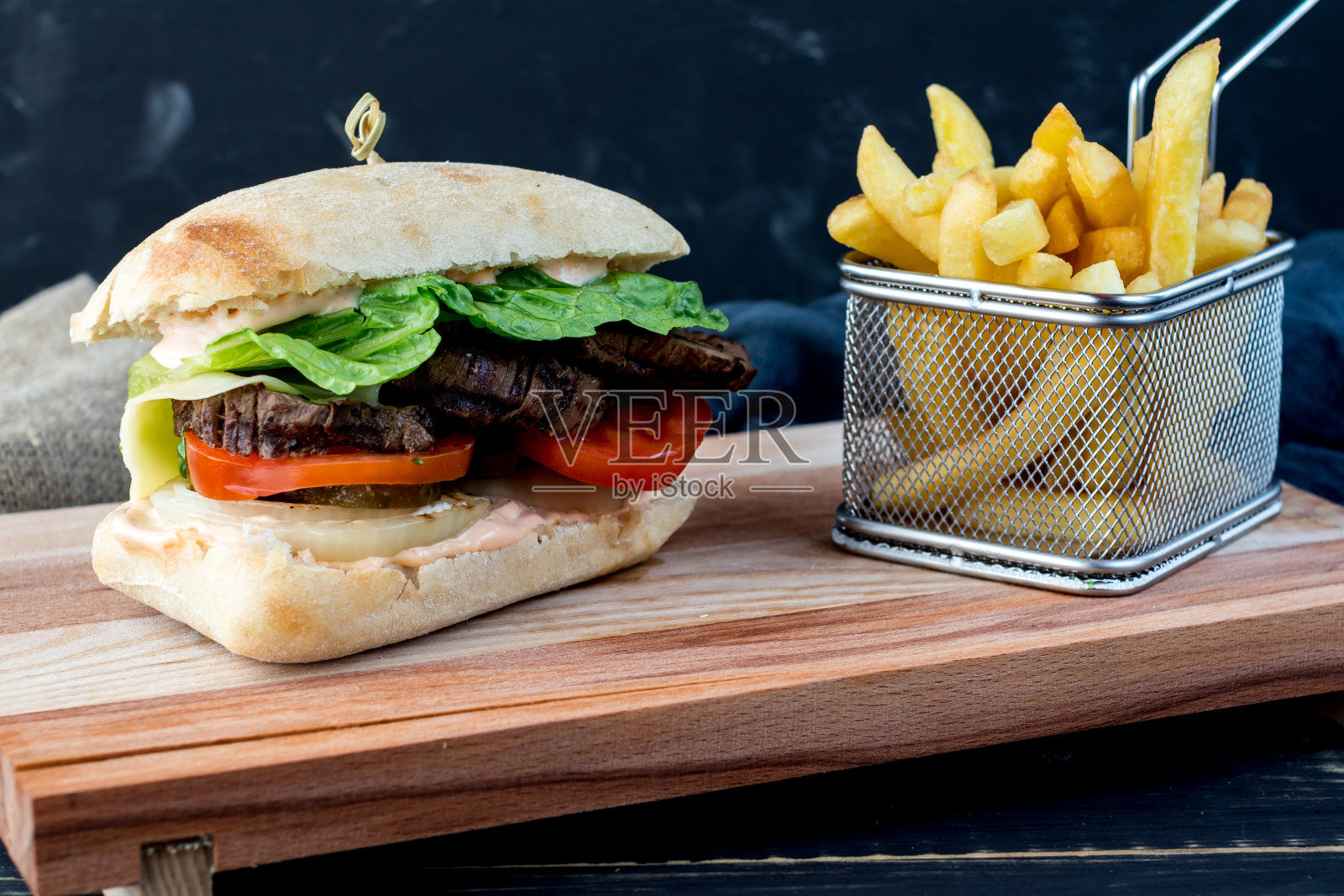 烤牛肉三明治配番茄和蔬菜沙拉放在木板上,配薯条照片摄影图片