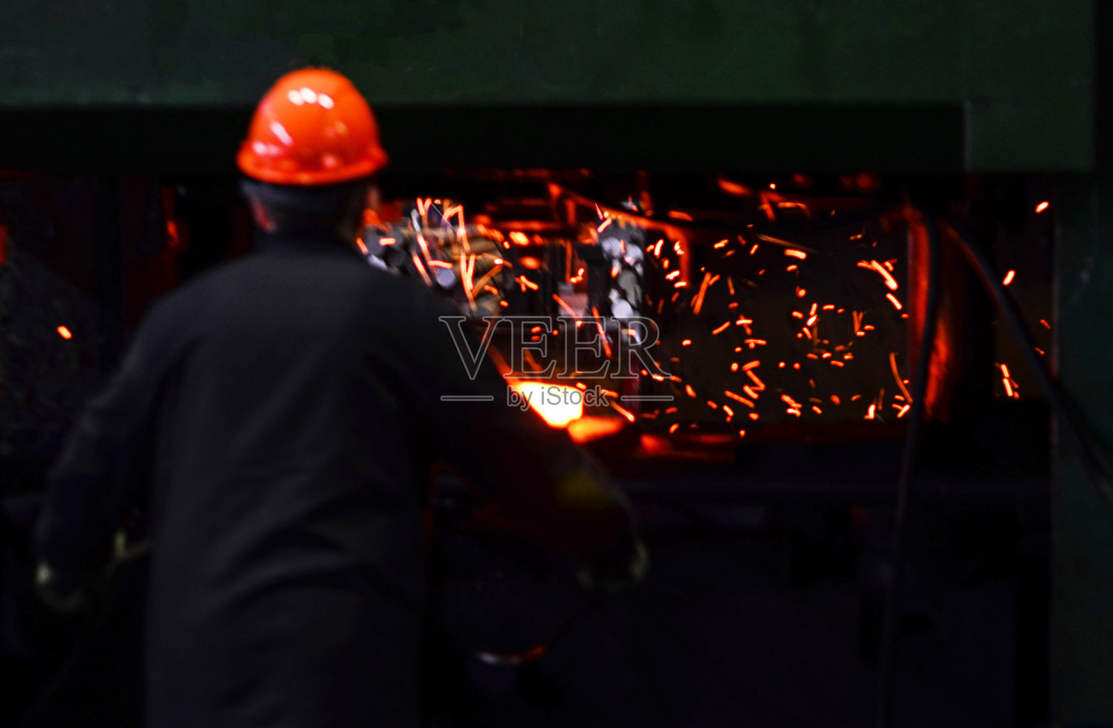 铁匠在冶金厂的压力机下用烧红的铁工作。锻造厂车间的金属锻件、冲压件。铁匠,炼钢和热轧厂。照片摄影图片