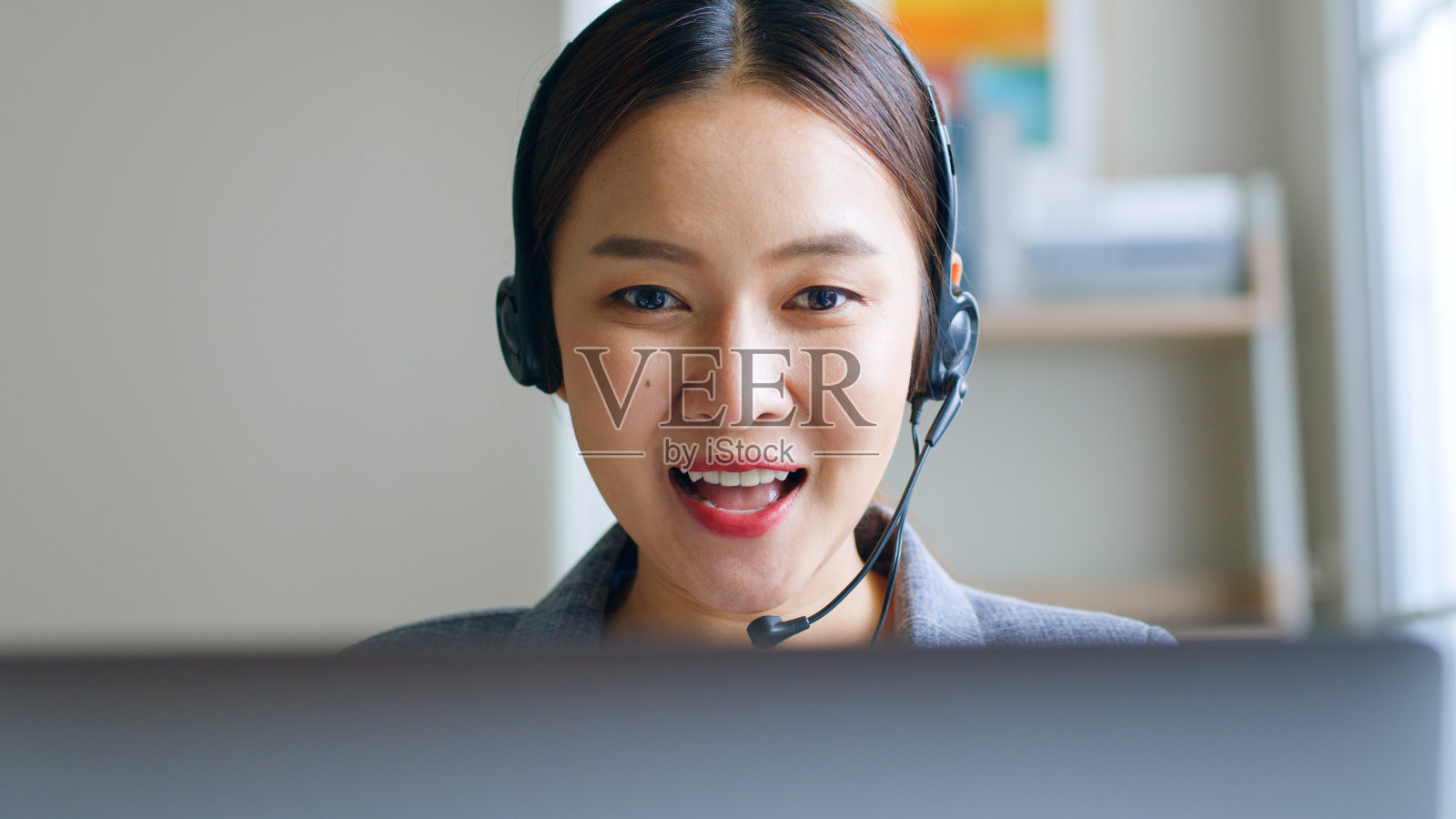 近距离的年轻亚洲女商人戴着耳机,呼叫中心,在办公室视频电话会议或虚拟会议的客户服务谈话,前视图照片摄影图片