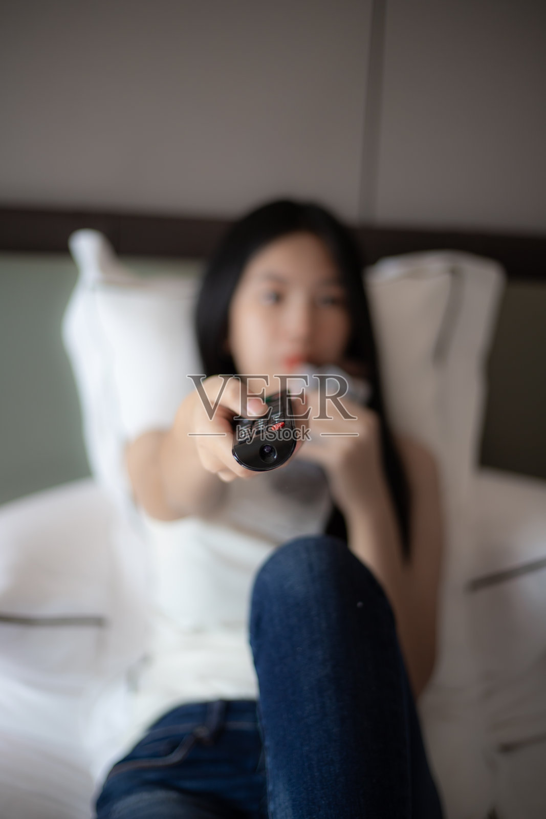 女人一边吃零食一边按电视遥控器照片摄影图片