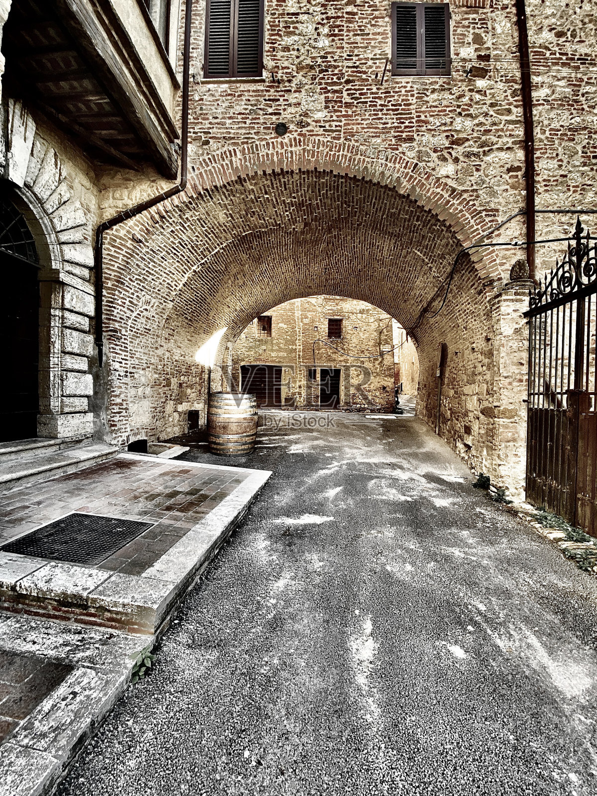 俯瞰中世纪的石头小巷,有石拱和一个风化的酒桶。照片摄影图片