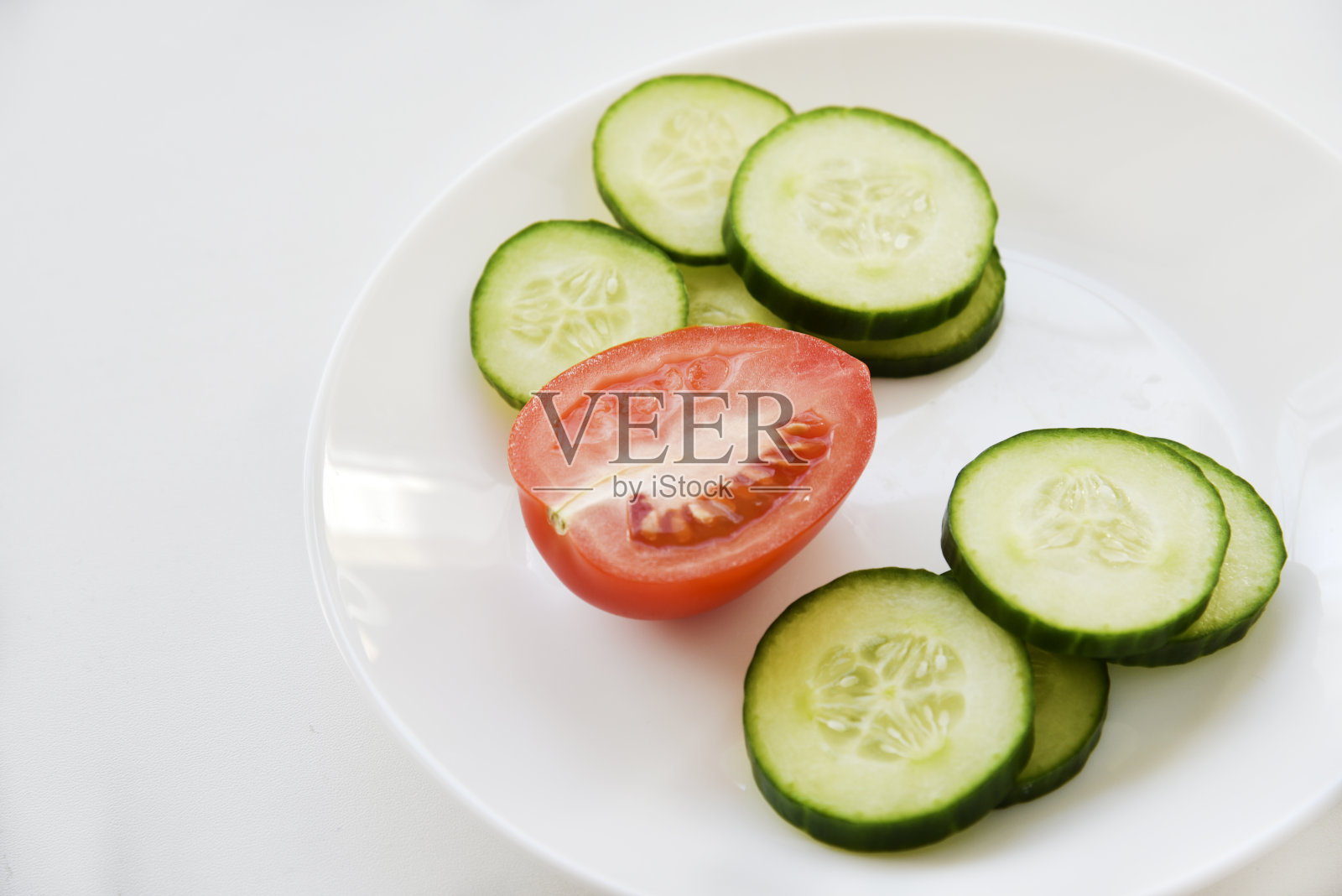 黄瓜片放在白色盘子里,还有西红柿照片摄影图片