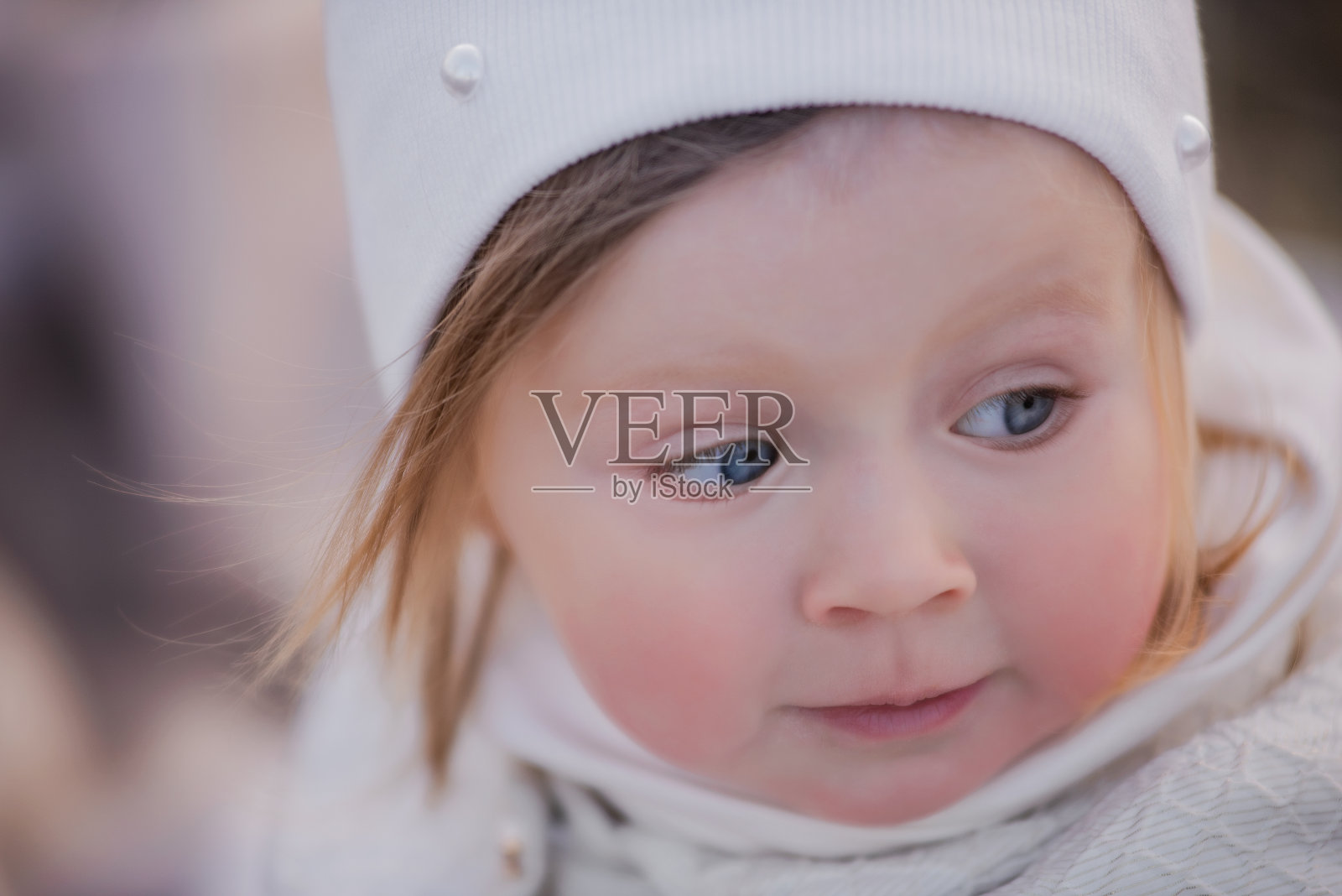 一个戴着白色帽子、蓝眼睛的金发小女孩的特写肖像。脸上有过敏照片摄影图片