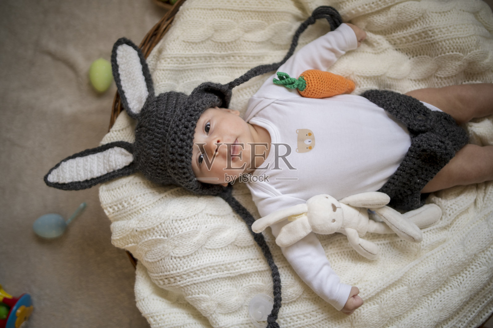 婴儿与兔子耳朵服装复活节躺在白色床上亚麻床单鹌鹑蛋。复活节儿童服装。照片摄影图片