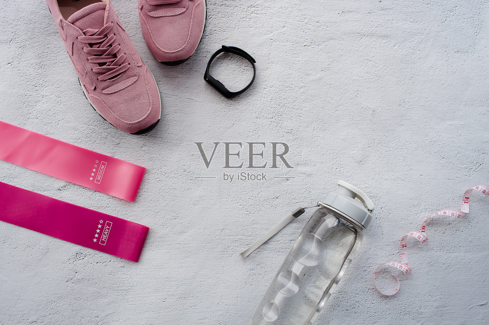 健康的生活方式和健身运动,晨跑。运动鞋,健身橡皮筋,智能健身追踪器,卷尺和一个灰色背景的水瓶。俯视图和平面布局。照片摄影图片