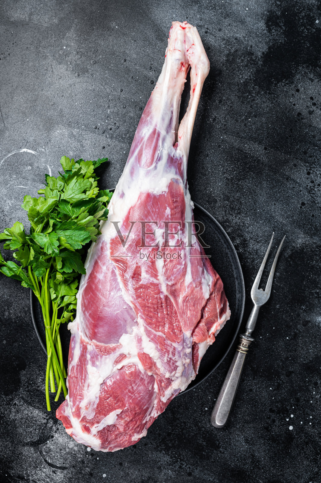 现准备烹煮生羊腿和羊腿。黑色背景。俯视图照片摄影图片