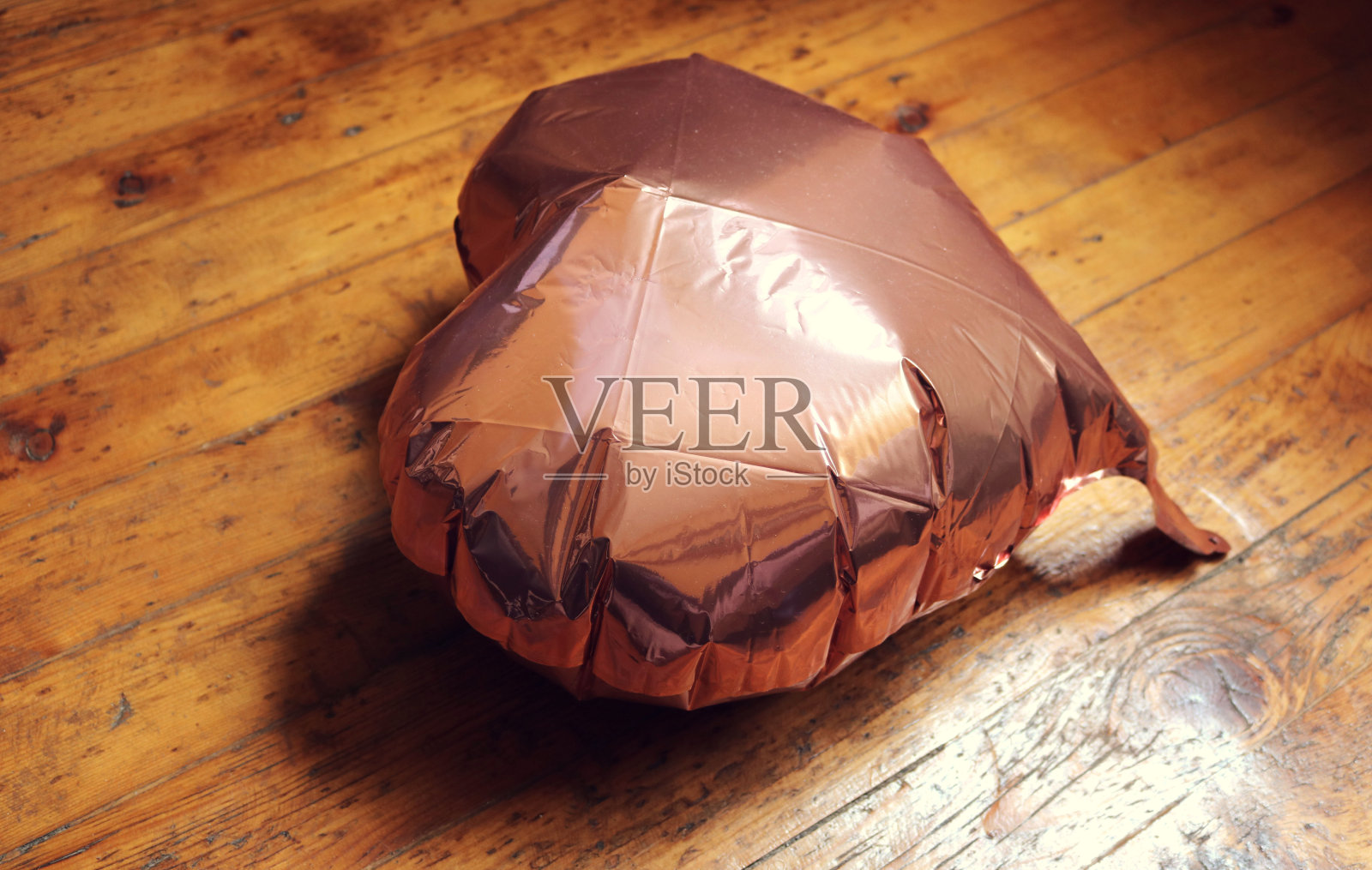 粉色心形充气气球,半泄气地躺在地上,象征失去爱或心碎。照片摄影图片