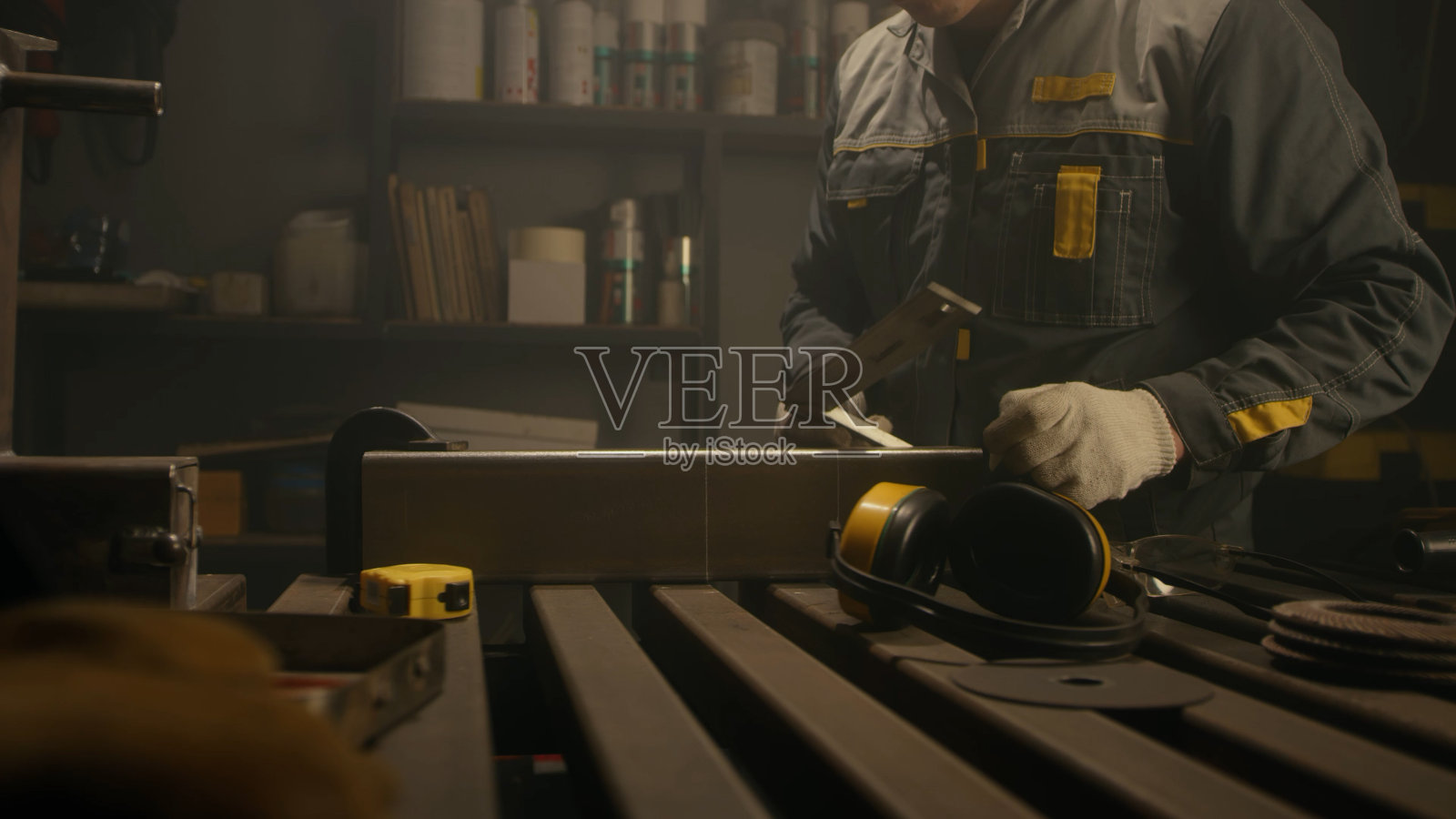 车间的金属工人用尺子测量,计算,用粉笔画衬线。穿着特殊衣服和护目镜的锁匠在生产中工作。缓慢的运动。近距离照片摄影图片