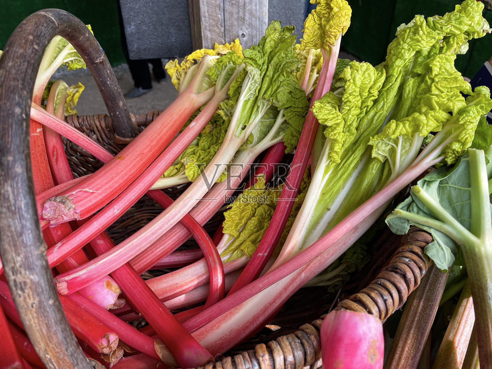 特写画面当地生鲜市场成堆的红绿大黄梗在柳条篮里,强迫春天大黄,聚焦前景照片摄影图片
