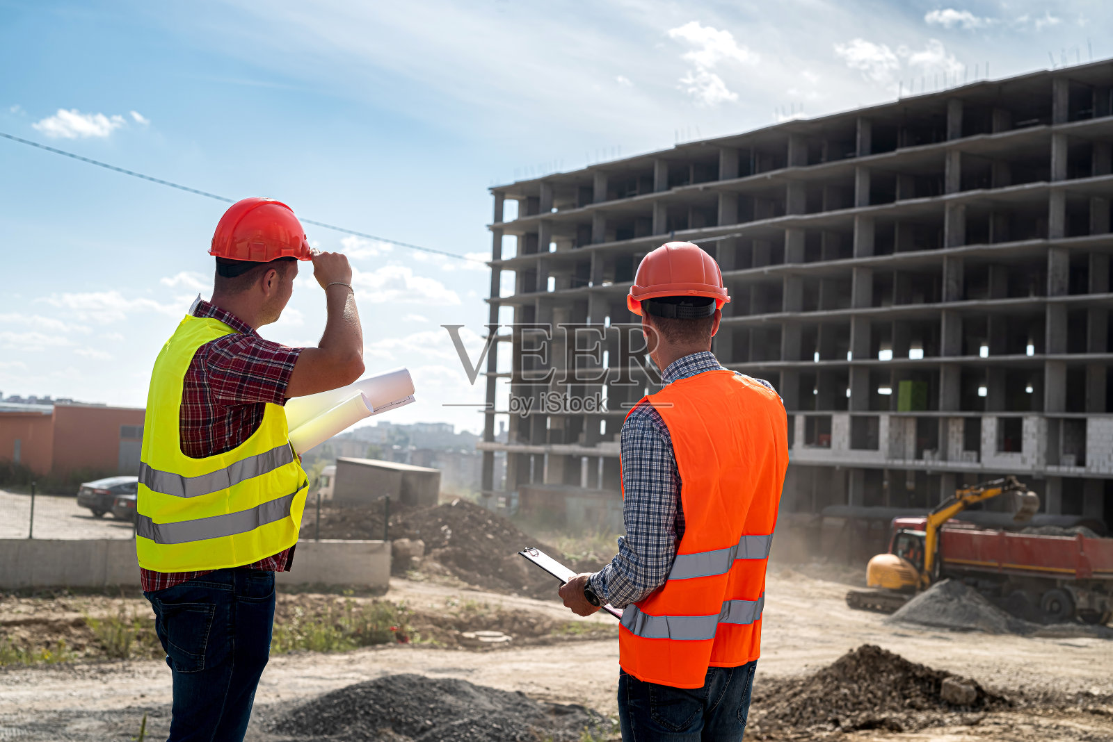 两个穿着制服的年轻工人在讨论盖房子的过程。照片摄影图片