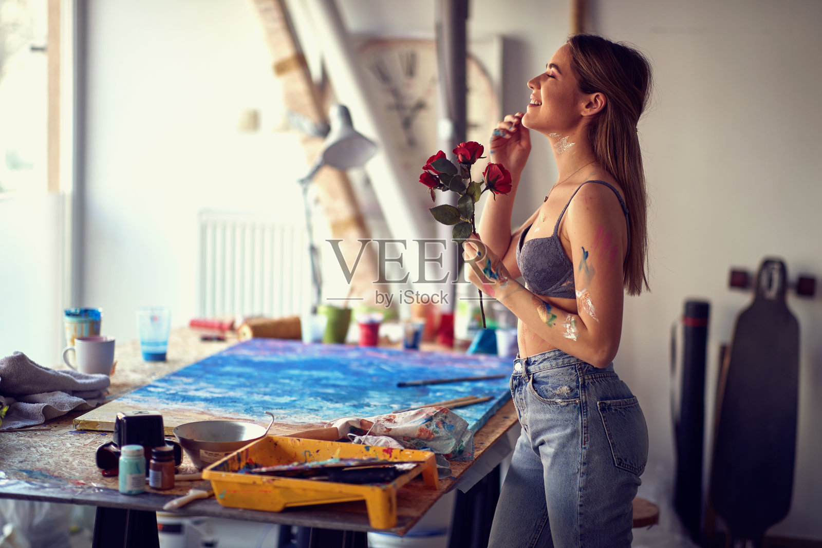 一个体贴的性感和有吸引力的女艺术家在她的工作室是狂喜的,而她得到的玫瑰。艺术、绘画、工作室照片摄影图片