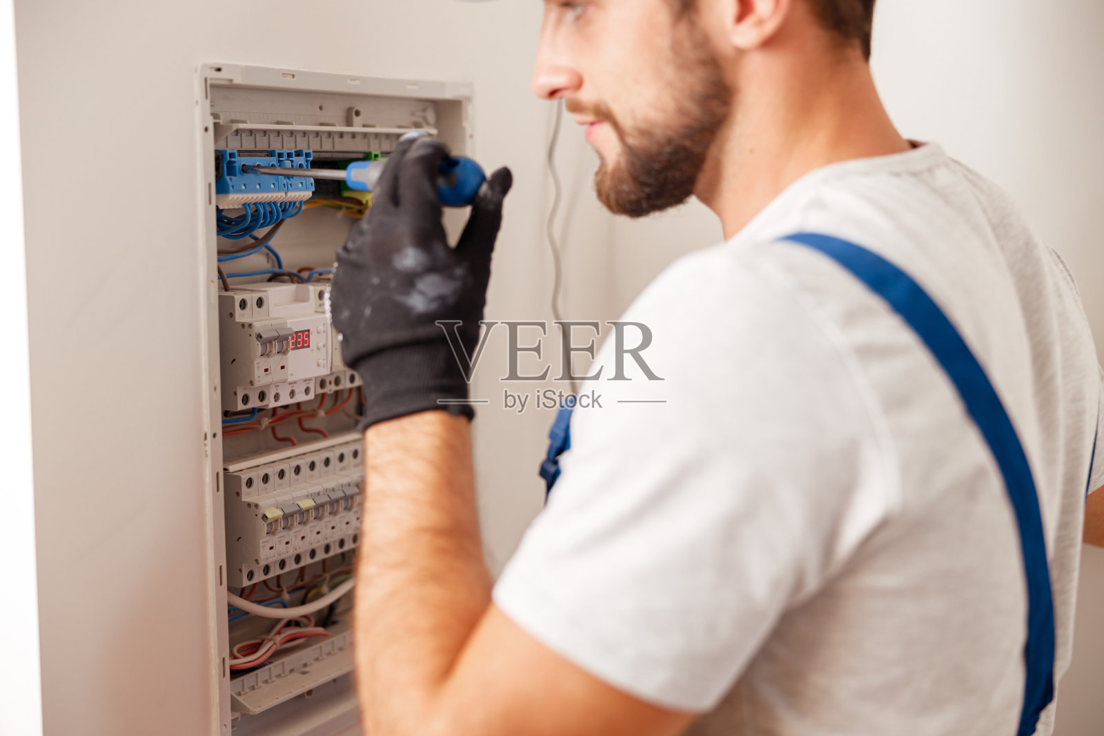 电气技术员在装有保险丝的配电盘内统一安装和连接电气设备照片摄影图片