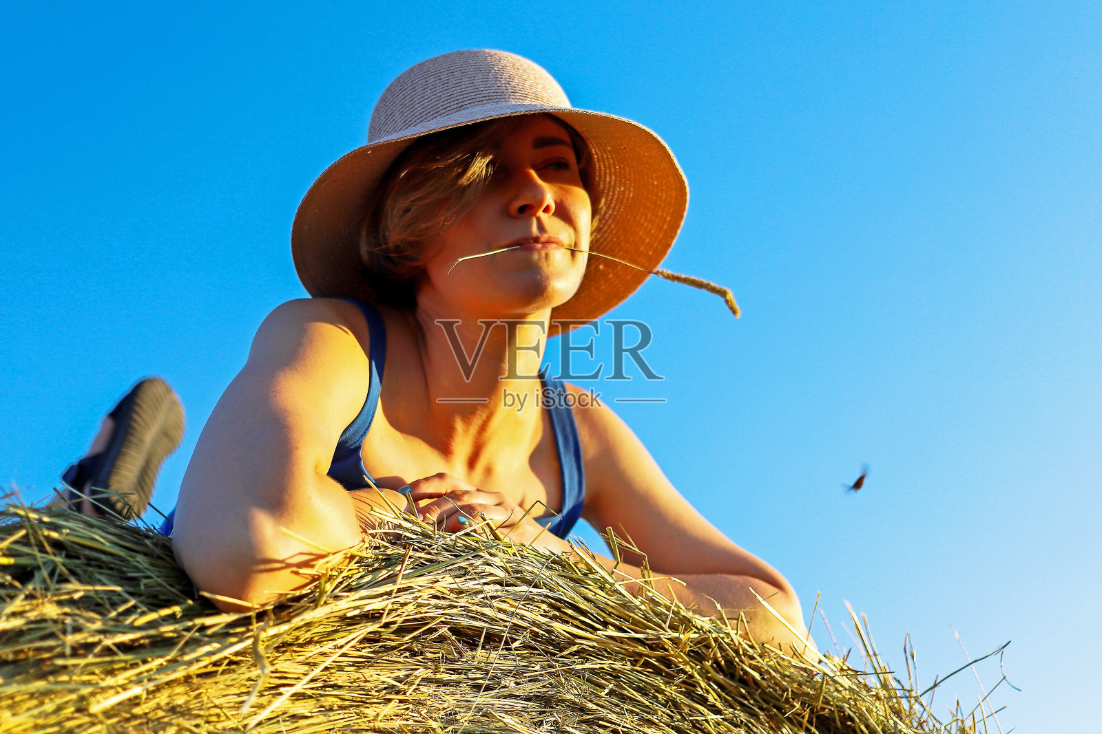 一个女孩在旷野的干草堆上休息照片摄影图片