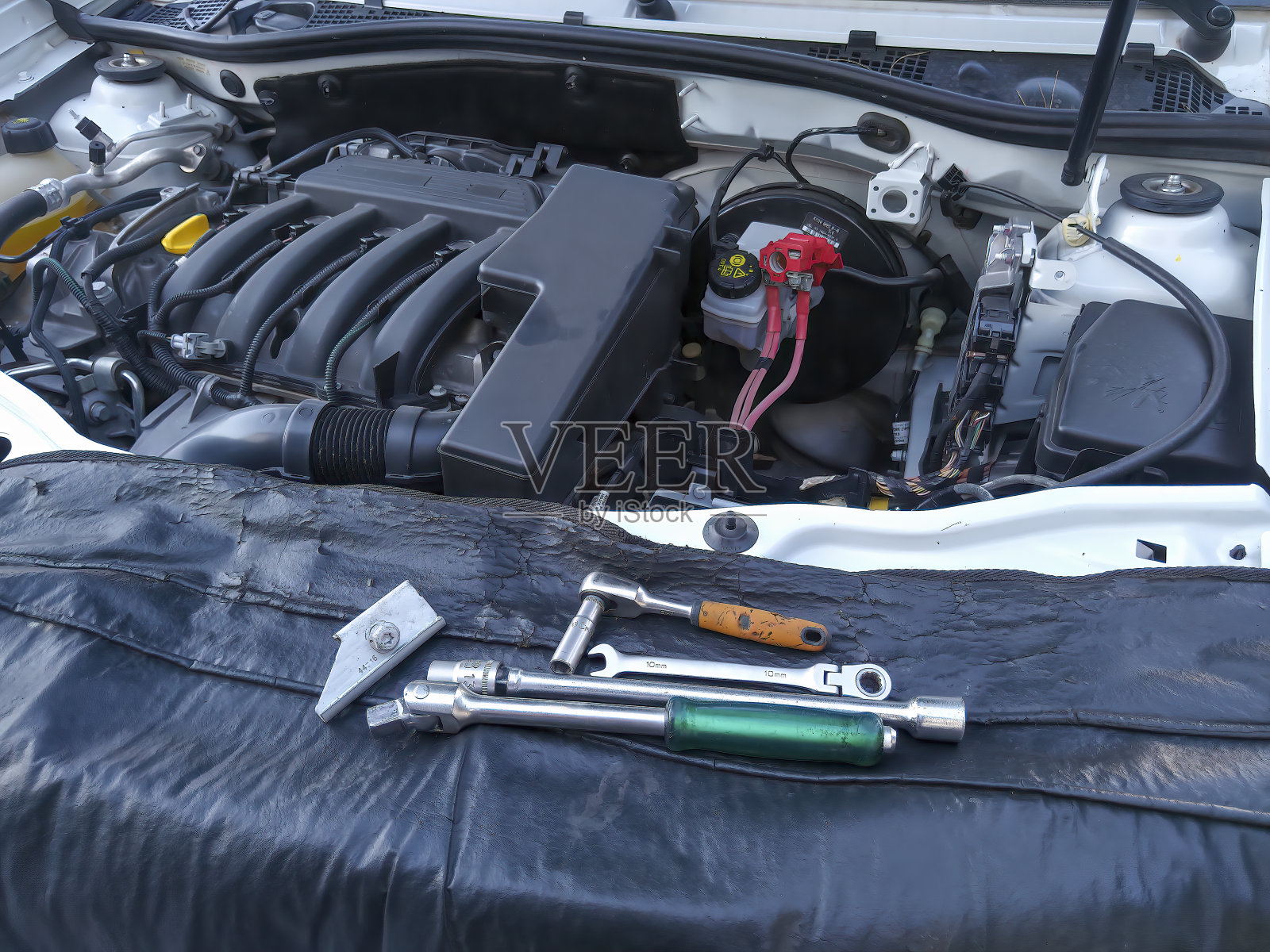 正在修理的汽车,引擎盖开着,没有电池。可见工作工具照片摄影图片