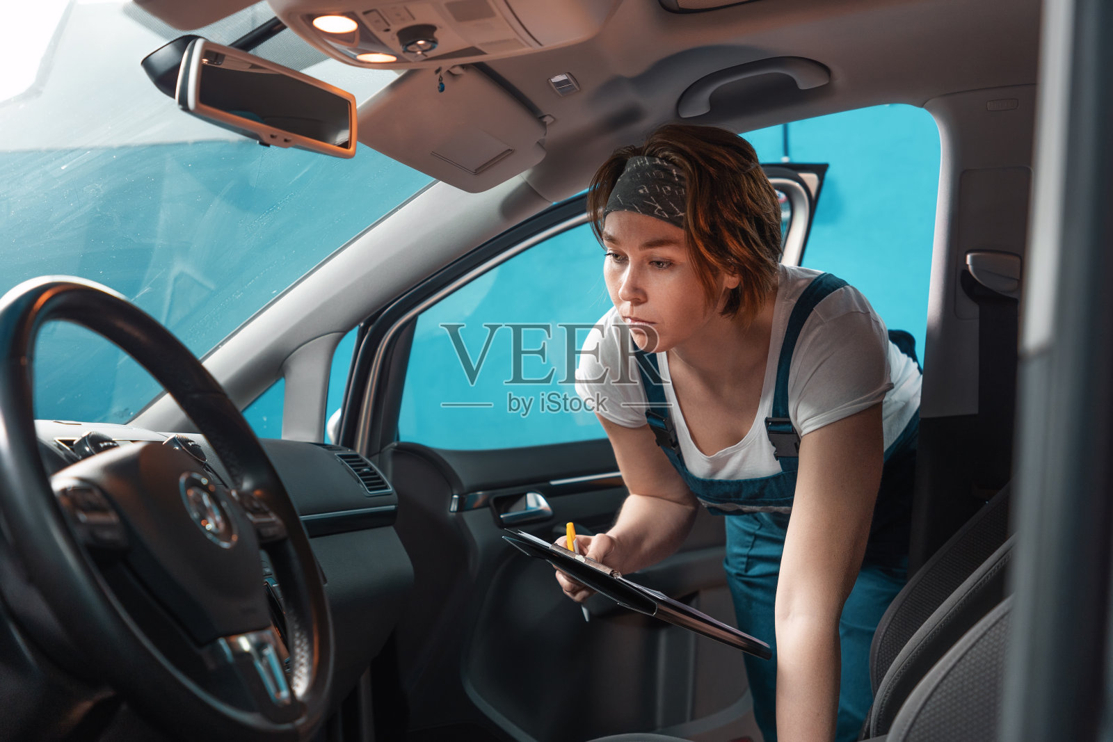 年轻的女机械师检查汽车内部。从汽车沙龙里面看。汽车清洁服务照片摄影图片