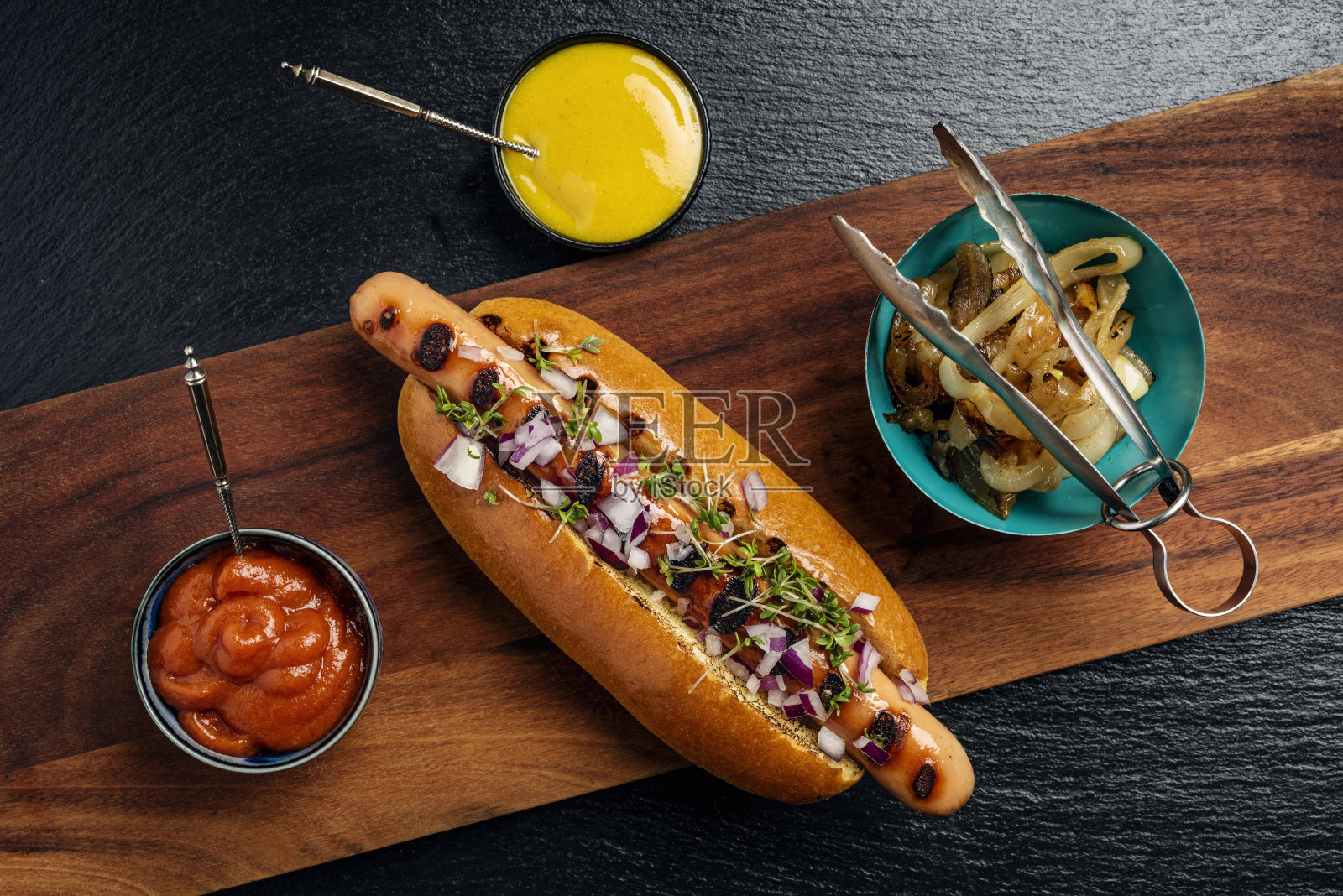 手工热狗在奶油卷与泡菜,洋葱和调味品。照片摄影图片