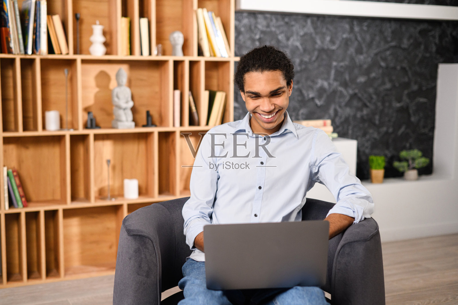 年轻的多种族男性学生观看网络研讨会,教育课程,远程学习,输入电子邮件。穿着休闲服的乐观民族男子坐着使用笔记本电脑照片摄影图片